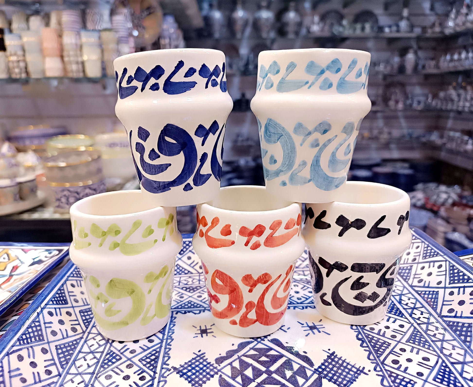 5 cups hand painted dishwasher safe cups with Arabic calligraphy in blue, green, red, and orange on a decorative tray.